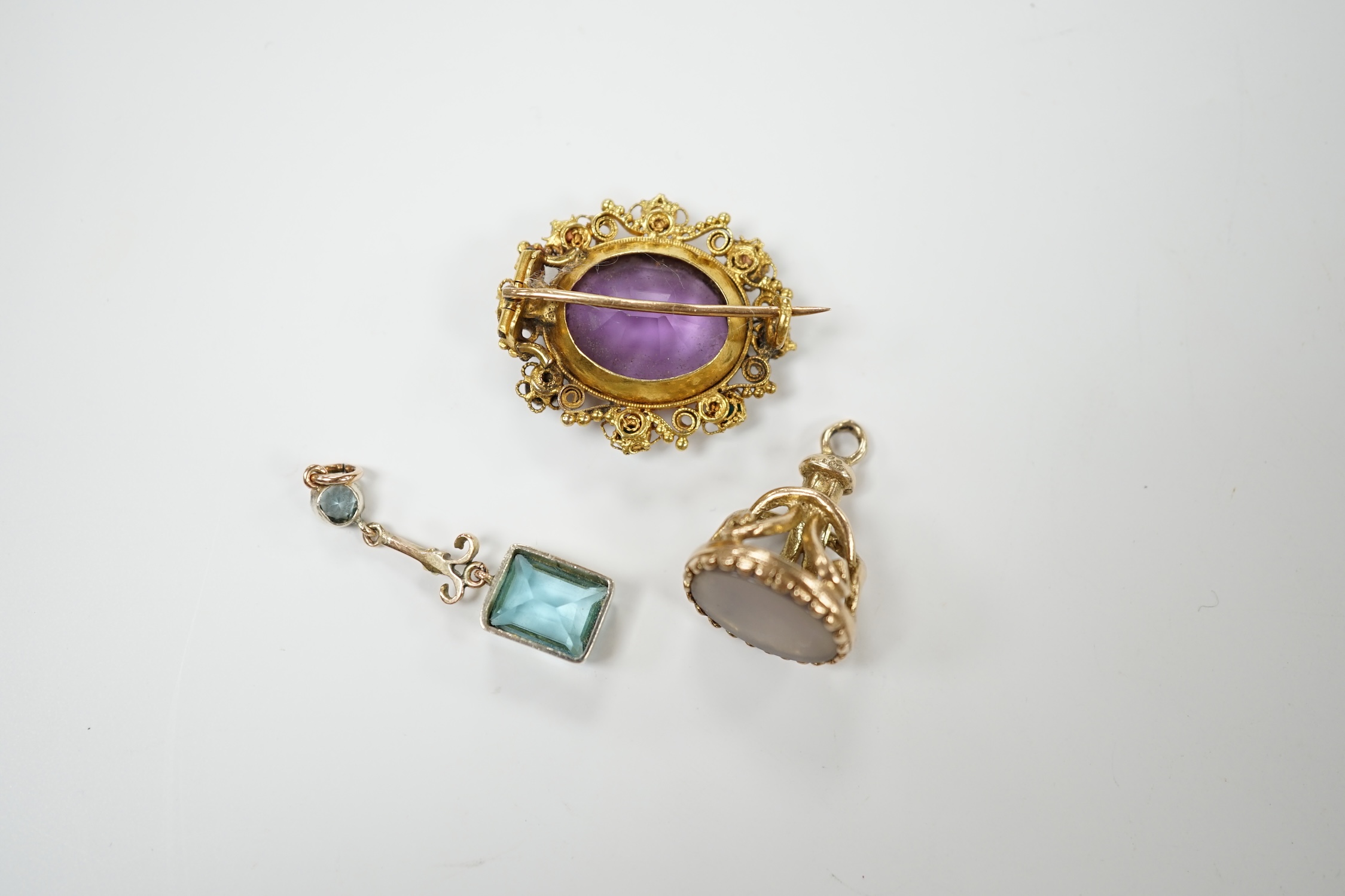An early 20th century yellow metal, amethyst and turquoise set brooch, 25mm, a 9ct gold and white chalcedony set fob and a yellow metal and gem set drop pendant. Condition - poor to fair